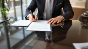 A person signing legal documents to complete the charitable donation of property for tax benefits.