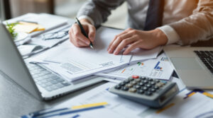 A person at a desk using a calculator to plan their end of year tax strategies for 2025.